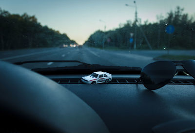 Close-up of vintage toy car on road seen through windshield in the evening 