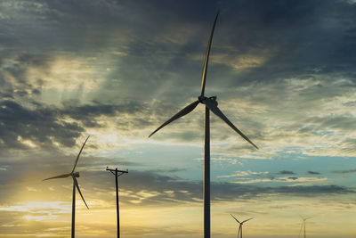 Low angle view of silhouette wind turbine against sky during sunset