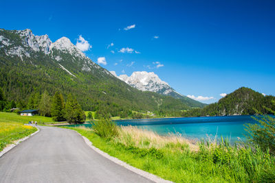 Road by mountains against blue sky