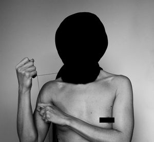 Rear view of shirtless man holding woman against white background