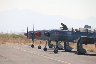 People at airport runway against sky