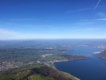 Aerial view of sea and mountains against blue sky
