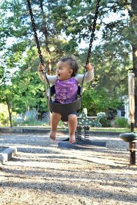 Full length of girl playing on swing at playground