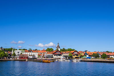 Buildings by river against clear blue sky