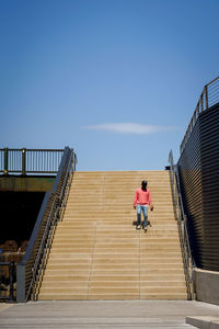 Man moving down on staircase against sky