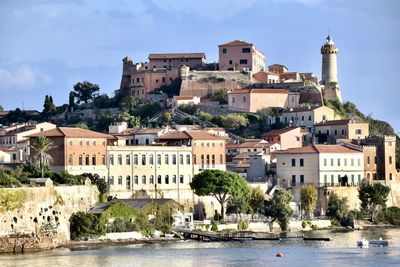 Buildings by river against sky