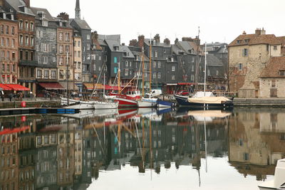 Boats moored in canal by buildings against sky