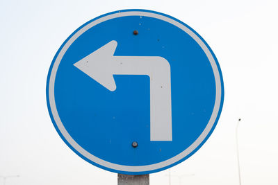 Close-up of road sign against white wall