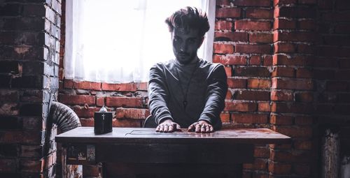 Man sitting on table against brick wall