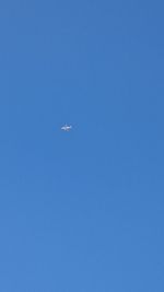 Low angle view of airplane wing against clear blue sky