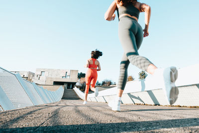 Low section of woman running against clear sky