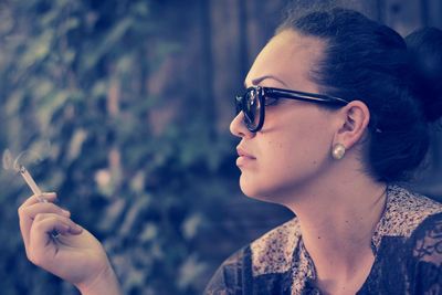 Close-up of young woman holding burning cigarette