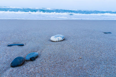 Close-up of pebbles on beach against sky