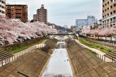 Footbridge in city against sky