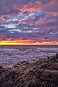 Scenic view of sea against dramatic sky during sunset