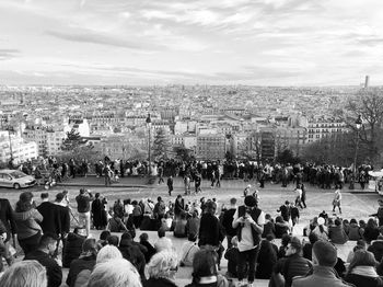 Group of people in city against cloudy sky