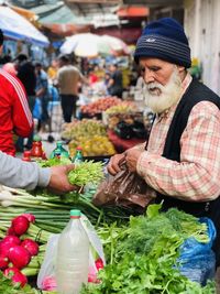 Man and vegetables for sale at market stall