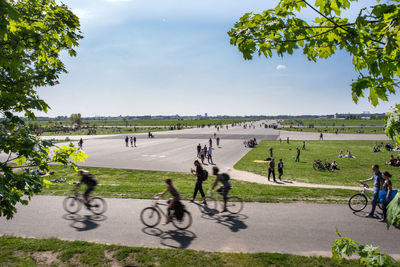 People riding bicycle on road against sky