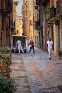 People walking on footpath amidst buildings in city