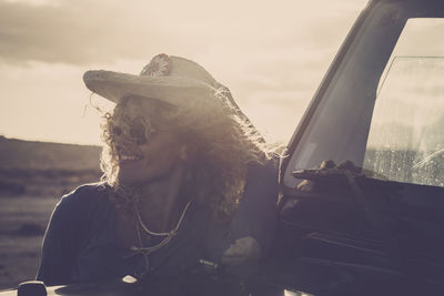 Portrait of young woman in car against sky