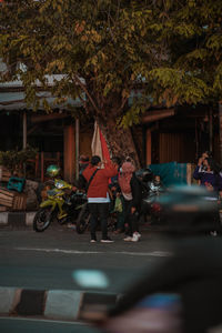 People on road amidst trees in city