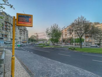 Road sign by building against sky