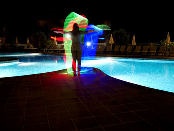 Rear view of woman in swimming pool at night