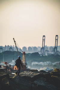 Man on rock against sky at sunset