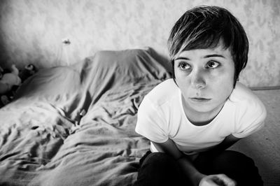 Portrait of teenage boy sitting on bed at home