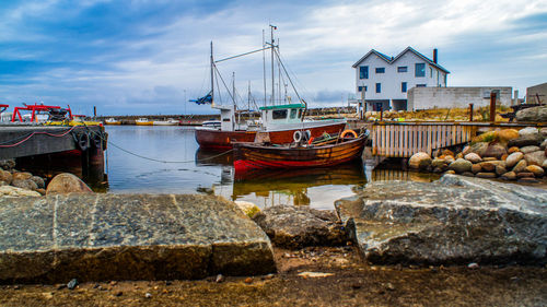 Boats moored at harbor against sky
