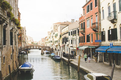 Canal amidst buildings in city against clear sky