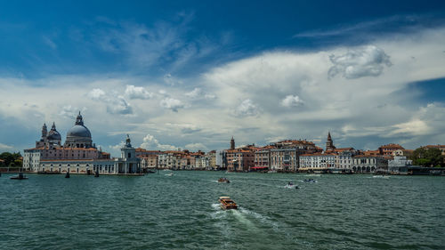 View of buildings at waterfront against cloudy sky