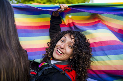 Woman looking at camera while holding a rainbow flag in an lgbtq pride march.