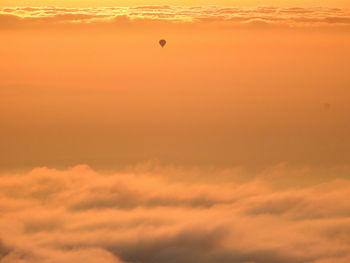 Silhouette hot air balloon against orange sky