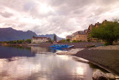 Buildings by river against sky