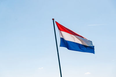 Low angle view of flag against blue sky