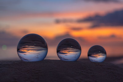 Close-up of sunglasses on beach against sky during sunset