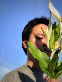 Close-up portrait of young woman with leaves against sky