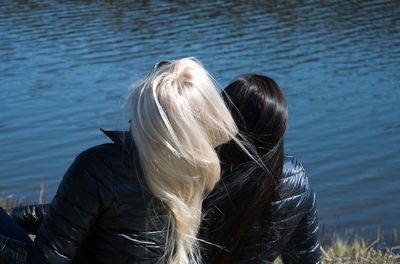 Rear view of friends sitting at lakeshore