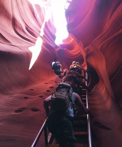 Low angle view of hikers climbing ladder amidst rock formations