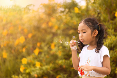 Full length of woman with bubbles standing against plants