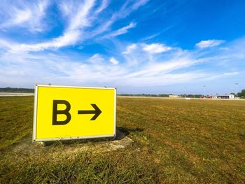 Information sign on field against sky