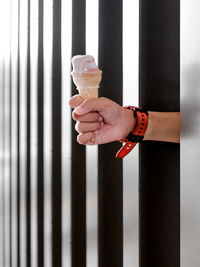 Hand holding ice cream cone between steel post