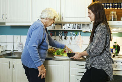 Grandmother and granddaughter preparing food in kitchen