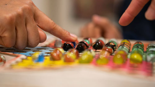 Cropped image of people playing with marbles on colorful container