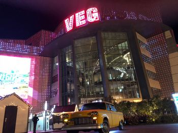 Cars on illuminated street amidst buildings in city at night