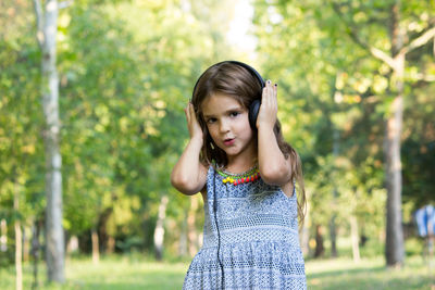 Smiling girl listening music while standing at park