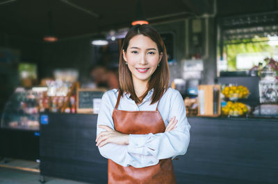 Portrait of smiling female owner standing in coffee shop