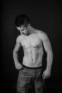 Full length of shirtless man standing against black background