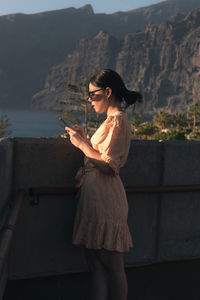 Young woman looking at camera while standing on railing